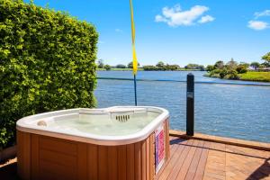 a hot tub sitting on a deck next to a body of water at The Old Bank Gladstone Licensed Restaurant & Boutique Accommodation in Hat Head