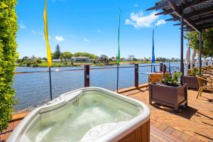 a hot tub on a deck next to the water at The Old Bank Gladstone Licensed Restaurant & Boutique Accommodation in Hat Head