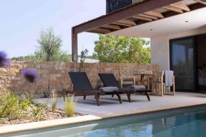 a patio with two lounge chairs next to a swimming pool at Pnoes Luxury Suites in Paliouri