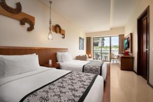 a hotel room with two beds and a table at MERUSAKA Nusa Dua in Nusa Dua