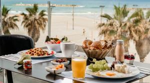 een tafel met ontbijtproducten en uitzicht op het strand bij Crowne Plaza Tel Aviv Beach, an IHG Hotel in Tel Aviv