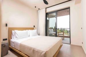 a bedroom with a large bed and a balcony at Pnoes Luxury Suites in Paliouri