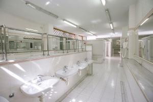 un bagno bianco con tre lavandini e specchi di Kampaoh Tossa de Mar a Tossa de Mar