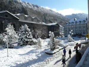 Un gruppo di persone che camminano nella neve vicino a un edificio di Marie locations hyper centre a Le Mont-Dore
