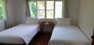 two beds in a room with two windows at บ้านรับพร in Nakhon Phanom