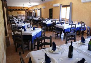 um restaurante com mesas brancas e cadeiras com guardanapos azuis em Kampaoh Cabañeros em Navas de Estena