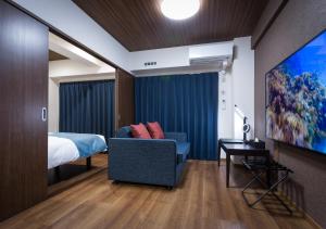 Habitación con cama, sofá y TV. en Ryujin Hotel Ukishima, en Naha