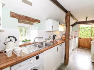 a kitchen with white cabinets and a sink at Jacky Garth Cottage in Keswick