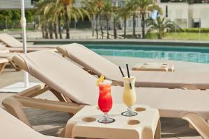dwa koktajle siedzące na stole obok basenu w obiekcie Hotel Bristol 4 Sup w mieście Benidorm