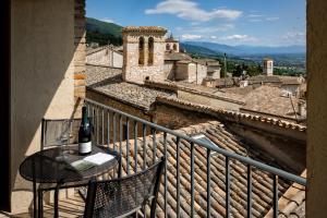 Una botella de vino sentada en una mesa en un balcón en Hotel Posta Panoramic Assisi, en Asís