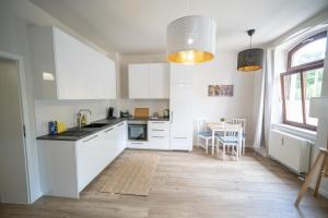 a kitchen with white cabinets and a wooden floor at FULL HOUSE Studios - L96 2 Bedroom Apartment in Zwickau