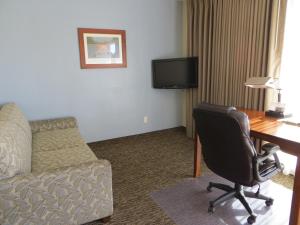 Habitación de hotel con escritorio, silla y sofá en Coronet Motel en Palo Alto
