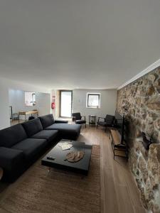 uma sala de estar com um sofá e uma parede de pedra em Casa dos Bernardos em Trancoso