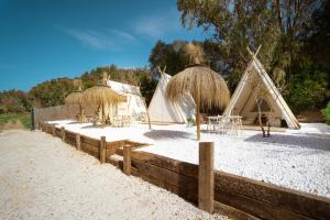 un gruppo di capanne con tavoli e sedie sulla spiaggia di Kampaoh Valdevaqueros a Tarifa