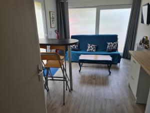 Una sala de estar con un sofá azul y una mesa. en Cabane des molieres, en Saint-Dié-des-Vosges