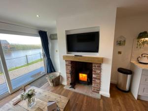 a living room with a fireplace with a flat screen tv at Maple Cove in Rawtenstall