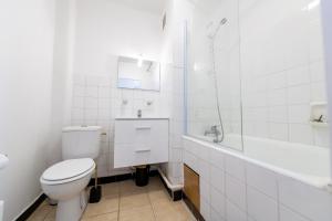 La salle de bains blanche est pourvue d'une douche et de toilettes. dans l'établissement Studio Lumineux Saint-Étienne Bellevue, à Saint Etienne