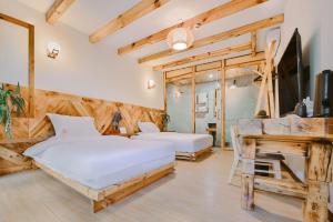 a bedroom with two beds and a tv and a desk at Swallow Nest Guesthouse in Kunming