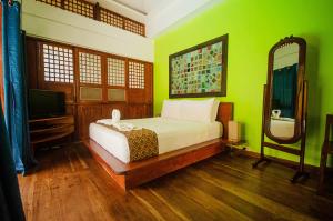 een slaapkamer met een bed met groene muren en een spiegel bij Balai sa Baibai in Mambajao