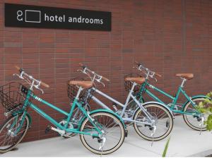 Tres motos están estacionadas junto a una pared de ladrillo. en hotel androoms Sapporo Susukino, en Sapporo