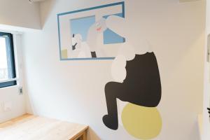 a bedroom with a wall mural of a person sitting on a chair at ART HOTELS SHIBUYA in Tokyo