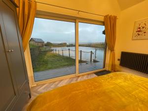 Schlafzimmer mit einem großen Fenster mit Blick auf das Wasser in der Unterkunft Cedar Lodge in Crawshaw Booth