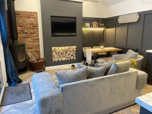 a living room with blue couches and a fireplace at Cedar Lodge in Crawshaw Booth