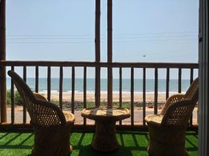 a balcony with two chairs and a table and the beach at Chivarin Resorts in Malvan