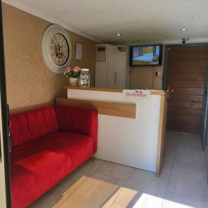 a red couch sitting next to a counter with a tv at High BnBGuestlodge in Johannesburg