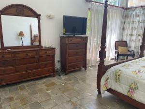a bedroom with a bed and a dresser with a television at VILLA CON Piscina en Juan Dolio in La Guáyiga