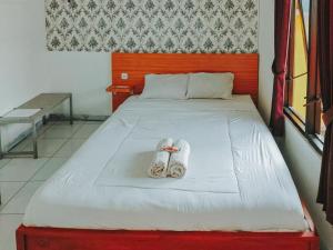 een bed met twee paar slippers erop bij De Luck Homestay near Alun Alun Sidoarjo Mitra RedDoorz in Sidoarjo