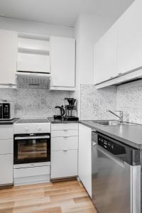 biała kuchnia z białymi szafkami i zlewem w obiekcie Majoituspalvelu Nurmi Oy City Apartment Kauppakatu 52 w mieście Raahe