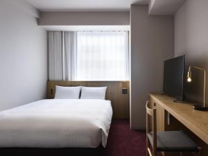 a hotel room with a bed and a television at hotel androoms Sapporo Susukino in Sapporo