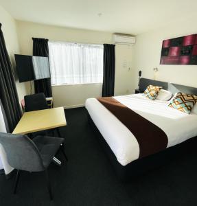 Habitación de hotel con cama grande y escritorio. en 298 Westside Motor Lodge en Christchurch
