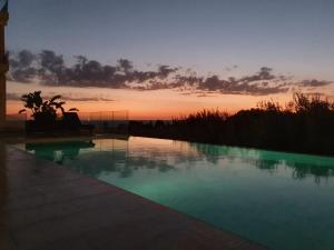 a swimming pool with a sunset in the background at Casa Costa Suites in Kanali