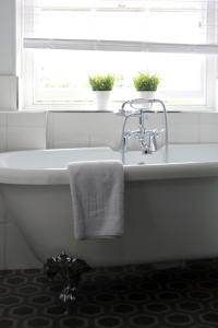 eine weiße Badewanne mit einem Handtuch und einem Fenster in der Unterkunft Luxury 3 Bed Apartment in the Heart of Stamford in Lincolnshire