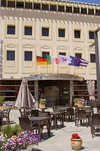 a restaurant with tables and umbrellas in front of a building at HR Hotel in Monfalcone