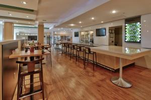 a restaurant with a bar and some tables and chairs at Holiday Inn Roswell by IHG in Roswell