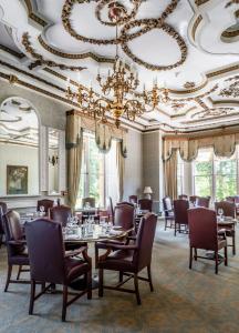 a dining room with tables and chairs and a chandelier at Ettington Park Hotel, Stratford-upon-Avon in Stratford-upon-Avon