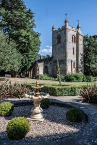 een fontein midden in een tuin voor een kasteel bij Ettington Park Hotel, Stratford-upon-Avon in Stratford-upon-Avon