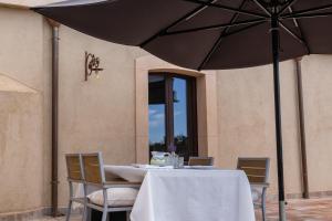 a table with chairs and a black umbrella at La Cantina Villa di campagna in Acireale