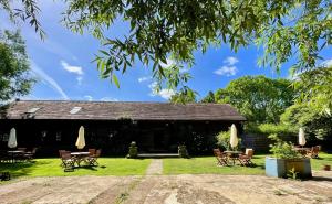 a building with chairs and tables in the grass at The Timber Barn South Downs West Sussex Sleeps 18 in Hardham