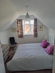 a bedroom with a bed with purple pillows and a window at Bexhill Sea View Flat 3 in Bexhill