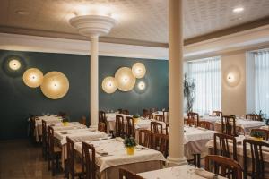 uma sala de jantar com mesas brancas e cadeiras de madeira em Hotel Catalunya Ribes de Freser em Ribes de Freser
