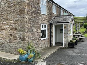 霍特惠斯爾的住宿－Milecastle Inn on Hadrian's Wall near Haltwhistle，一座石头建筑,前面有两颗蓝色花瓶