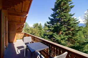 einen Balkon mit einem Tisch und Stühlen sowie einem Weihnachtsbaum in der Unterkunft 5min. from the ski slopes Crans-Montana, 2 bedrooms, covered parking in Crans-Montana