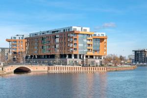 a large building next to a river with a bridge at Grand Apartments - Brabank Apartments in Gdańsk