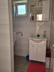 La salle de bains est pourvue d'un lavabo blanc et d'un miroir. dans l'établissement Apartment Nura, à Bihać