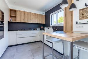 une cuisine avec des placards blancs et une table en bois dans l'établissement La Villa d'Ezer - Maison contemporaine 4-6 pers, à Loctudy