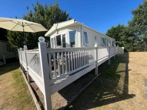 a white mobile home with an umbrella at 6 Berth Caravan With Decking At Cherry Tree Park In Norfolk Ref 70014g in Great Yarmouth